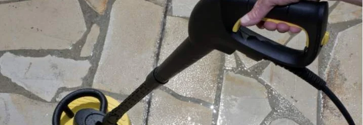 Person reinigt Fliesen mit Hochdruckreiniger